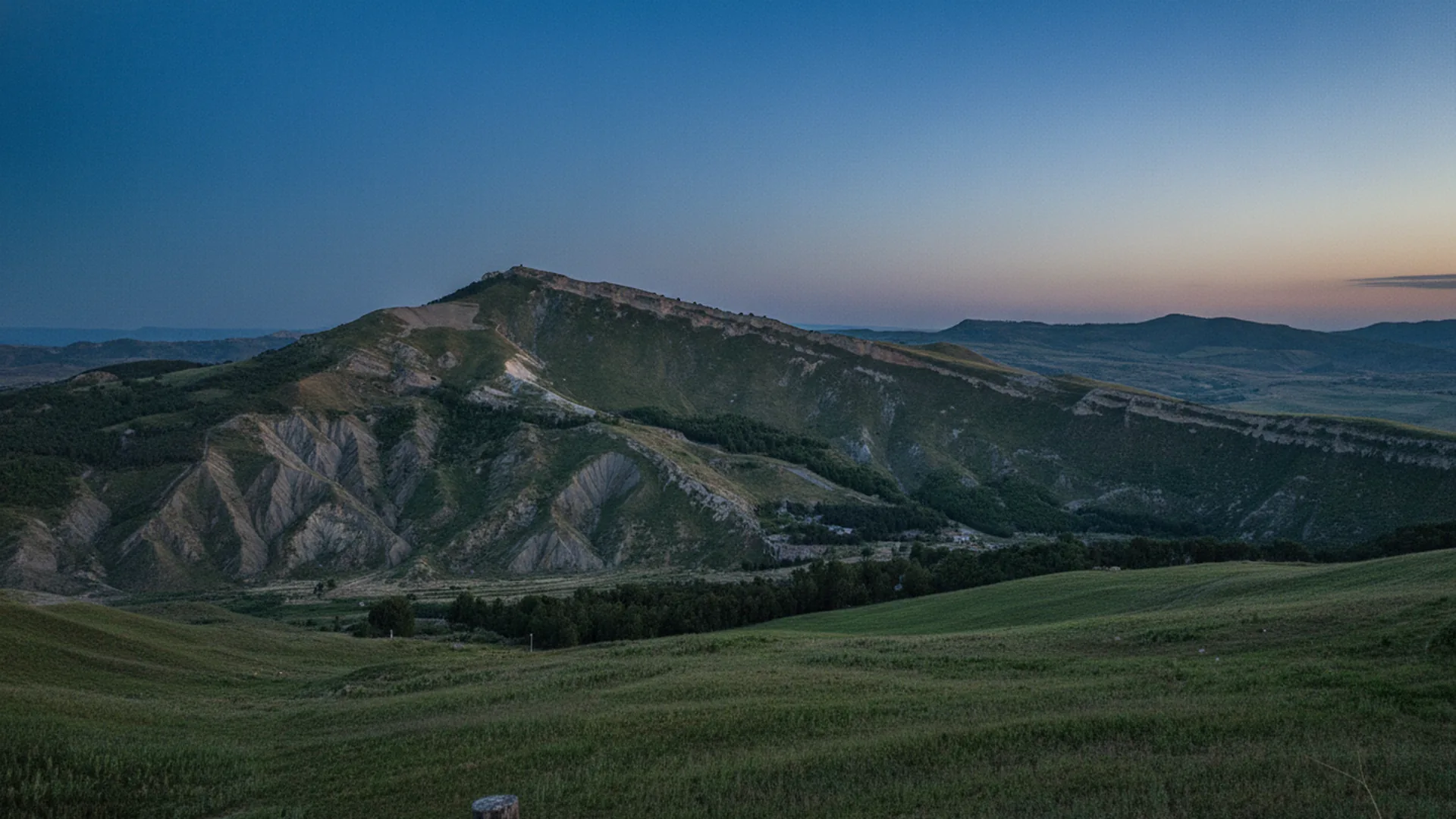 Il rilievo di Monte Capodarso al crepuscolo, con i calanchi argillosi e i prati della Valle dell'Imera Meridionale